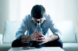man in business attire drinking with head down