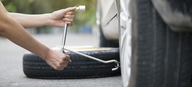 woman loosening lug nuts to change a tire