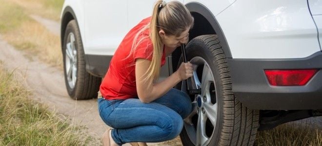 a woman changes a tire on her car