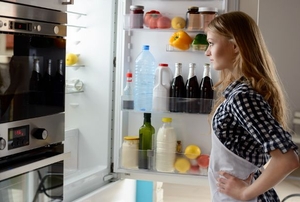 A woman standing in front of an open refrigerator.