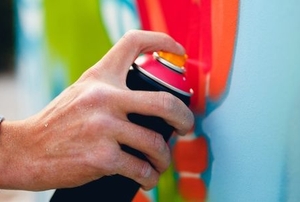 a hand spray painting a white surface with colors