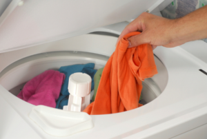 Person adding clothing to a washing machine