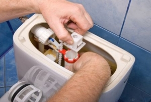 A man fixes the toilet tank