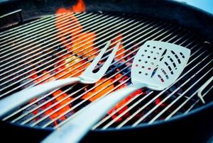 A grilling fork and spatula on a burning barbecue.