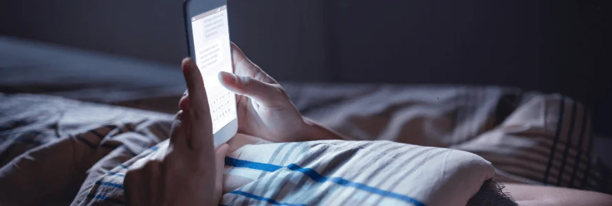 Teen Sexting Laws and Penalties person holding phone late at night in bed