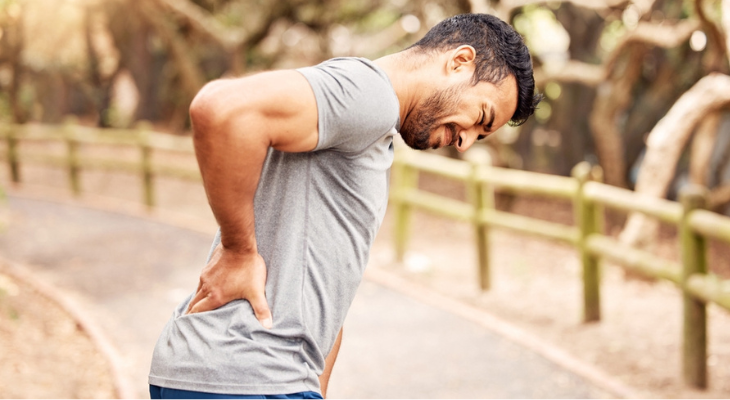Man holds his back in pain.
