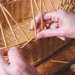 Hands weaving a basket