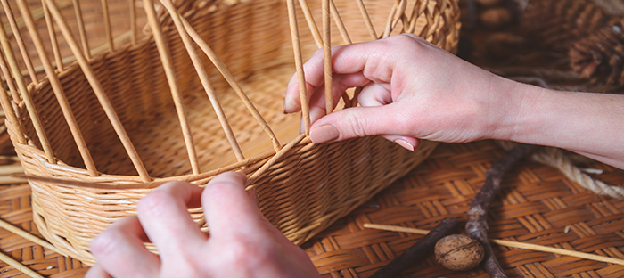 Hands weaving a basket