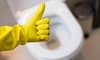 A hand in a yellow glove giving the thumbs up sign in front of a toilet.