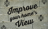 The phrase, "Improve your home's view" on a cinderblock brick wall