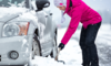 Woman shoveling snow to free her car on the road