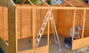 Man constructing a wooden shed