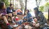 A group of friends gathering around a meal while camping.