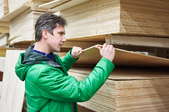 A man in a green jacket choosing plywood.