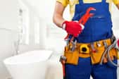 plumber wearing a tool belt and holding a large wrench