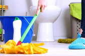 a woman cleaning a bathroom floor with a mop.