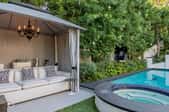 patio cabana with cushions and a chandalier next to a pool