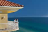 A couple on the balcony of a beach house, overlooking the ocean.
