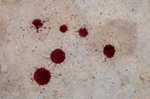 Several blood droplets on a concrete surface.