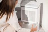 woman removing tray from dehumidifier