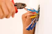 A handyman works on wiring in a home.