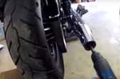 hand drill inserted into motorcycle exhaust pipe