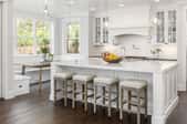 a large open white kitchen with island and stools