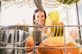 smiling woman loading or unloading dishwasher