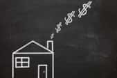 A chalkboard drawing of a house burning money. 