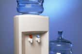 A water cooler with an extra jug beside it.