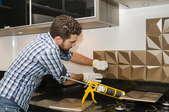 man installing or removing metal backsplash in kitchen