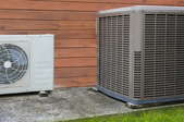 A heat pump mounted beside an air conditioner unit.