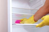 Cleaning a glass refrigerator shelf with an abrasive pad.