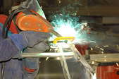 A worker in a fabrication shop welding aluminum.