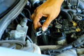 A hand securing an ignition coil in place inside an engine.