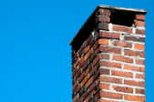 A worn, brick chimney against a blue sky.