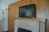 paneled wall with brick fireplace mantle and television above it
