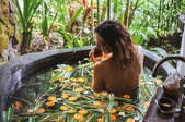 woman in outdoor bath tub spa with leaves and fruit