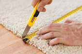 hands measuring and cutting carpet