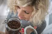 A woman smelling a jar of coffee beans. 