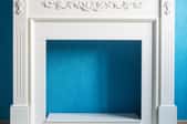 empty fireplace frame in front of blue wall