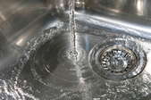 A stainless steel sink with water running down the drain. 