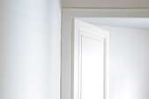 A white interior door sits ajar at the end of a hall.