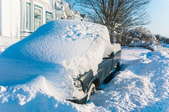truck buried in deep snow next to a house