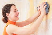 A woman wiping away wallpaper glue with a rag.