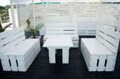 white wooden table on a deck surrounded by white wooden benches and fencing