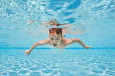 a young boy swimming underwater in a pool