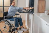 woman in wheelchair using accessible wall-mounted oven