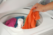 Person adding clothing to a washing machine