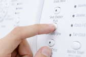 hand pushing buttons on an energy efficient clothes drier
